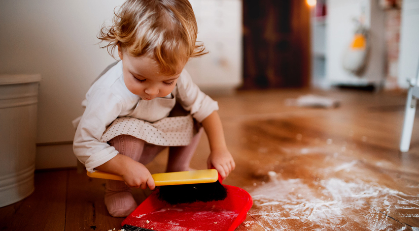 Child using dustpan and brush cleaning in a Montessori classroom