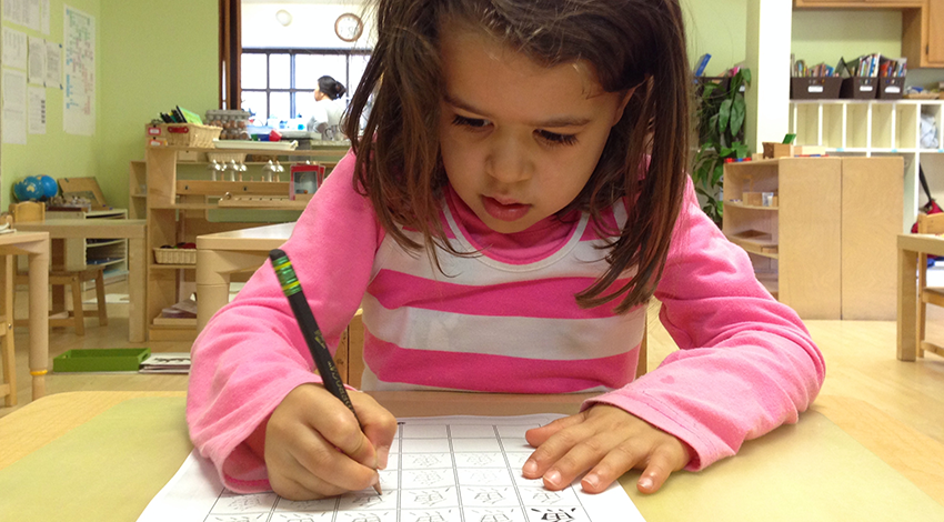 Child in Montessori classroom writing Chinese characters