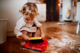 Child using dustpan and brush cleaning in a Montessori classroom